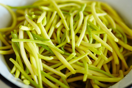 Closeup of a bowl of young pods of beans, uncooked