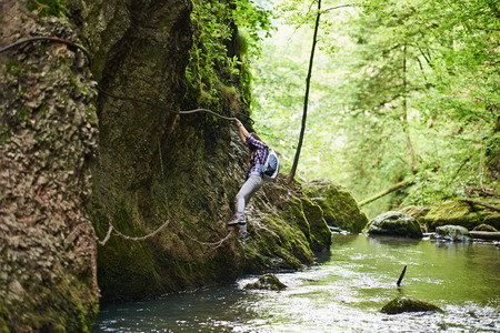 Young woman hiker climbing on safety cables in a gorge above the riverの写真素材