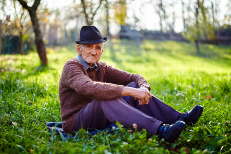 Old farmer sitting in grass at sunsetの写真素材
