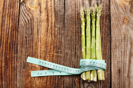 Concept of healthy diet with fresh asparagus and measuring tape on a wooden boardの写真素材