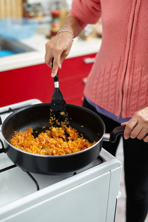Housewife cooking stir fry vegetables in a pan on a stoveの写真素材