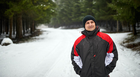 Outdoor winter portrait of a happy young man walking on a mountain trail