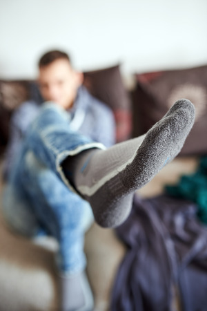 Teenager sitting on sofa with crossed legs, selective focus on footの写真素材