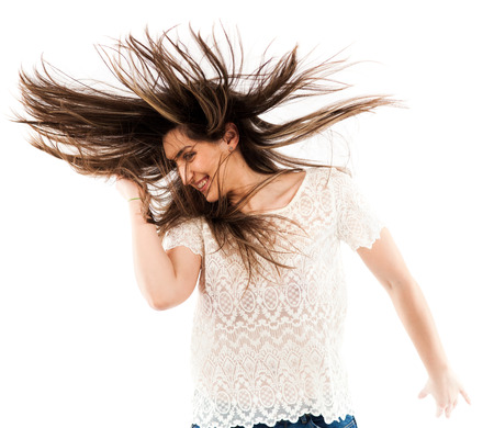 Cheerful woman flipping her hair while dancing isolated on white backgroundの写真素材