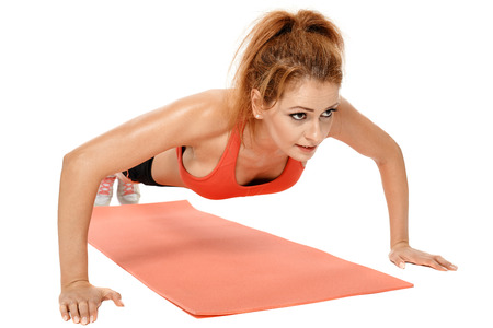 Young fitness woman doing exercises on a mat isolated on white