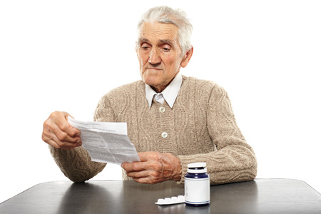 Caucasian senior man reading dosage instructions of some pillsの写真素材