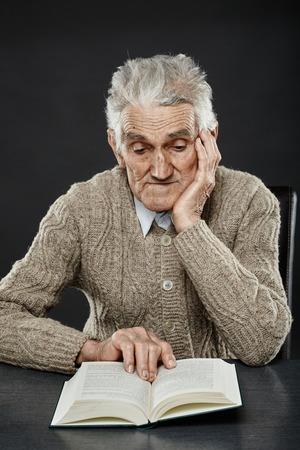 Old man reading a book, studio closeup portraitの写真素材