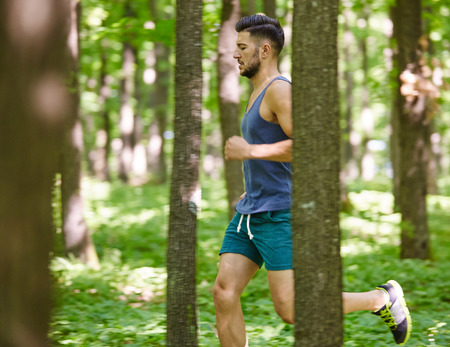 Young and fit runner on a trail run through forestの写真素材
