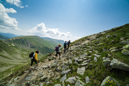 Family of hikers walking on a trail into the rocky mountains