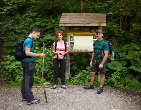Family of hikers standing in the forest near an information pointの写真素材