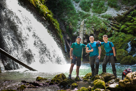 Three friends in holiday, posing near a waterfall in the canyonの写真素材