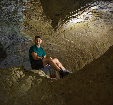 Happy man sitting on a large rock in a caveの写真素材
