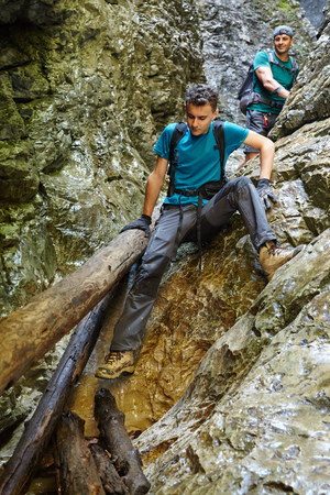 Male hikers going down through a very difficult canyonの写真素材