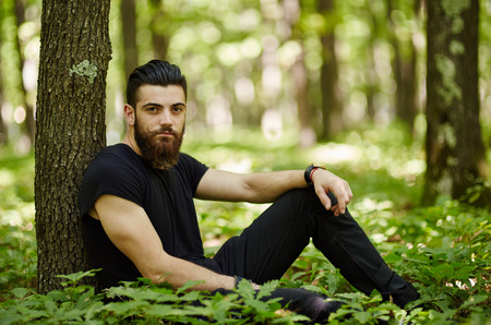 Fashionable young man posing in the woodsの写真素材