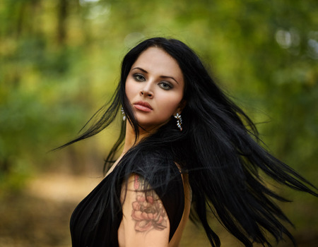 Gorgeous young woman running through a forest with her hair in the wind, closeup portraitの写真素材