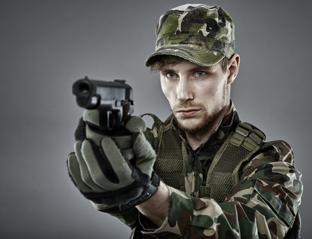 Military man holding a gun, ready to shootの写真素材