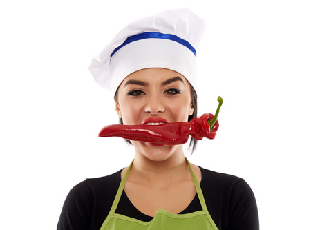 Young woman cook biting a big red pepper, closeup shotの写真素材