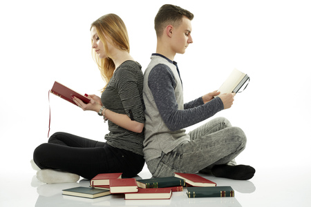 Teenage students doing homework together, with many books around themの写真素材