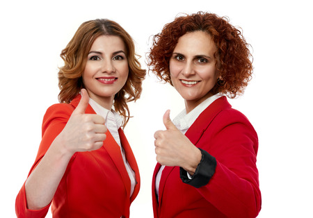 Businesswomen partners showing thumbs up sign on white backgroundの写真素材