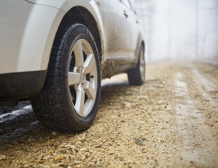 White SUV car on an offroad trail in a foggy day