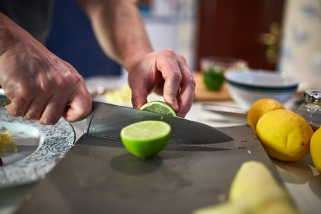 Hands of chef slicing limes on a board