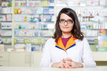 Closeup of a woman pharmacist over blurred background of shelves with medicineの写真素材