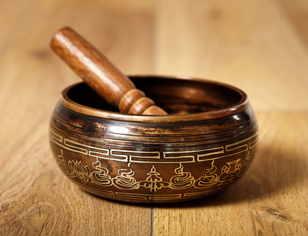 Closeup of an ancient tibetan bowl on woodの写真素材