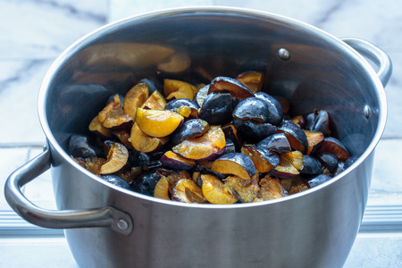Sliced plums in a stainless steel pot to make chutney or jamの写真素材