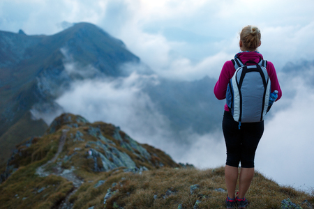 Young woman hiker with backpack walking a trail in rocky mountainsの写真素材