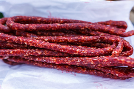 Closeup of dried smoked stick sausages on cooking paperの写真素材