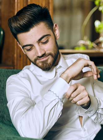 Elegant young man with beard sitting on a sofaの写真素材