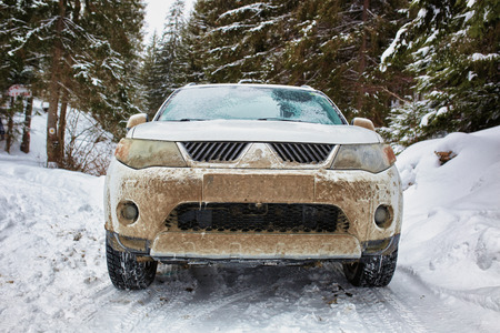 SUV car in the mountains on a snowy road near the forestの写真素材