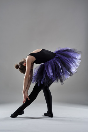 Young ballerina in various postures on gray backgroundの写真素材