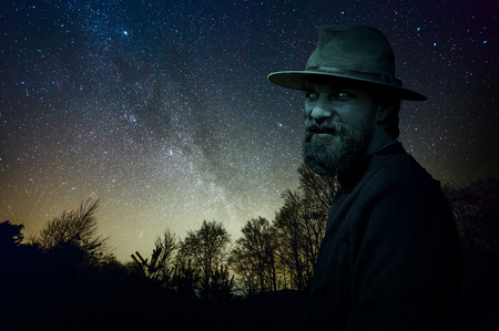 Scary man in hat and beard at night in a creepy forestの写真素材