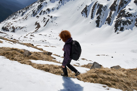 Woman hiking into the rocky  mountains at springtime
