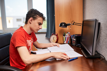 Teenager boy doing homework on his desk at homeの写真素材