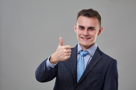 Young man in classic business suit, showing thumbs up signの写真素材