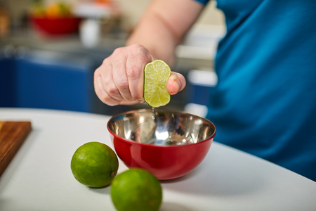 Man's hand squeezing a lime into a bowlの写真素材