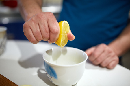 Man's hand squeezing a lemon into a bowlの写真素材