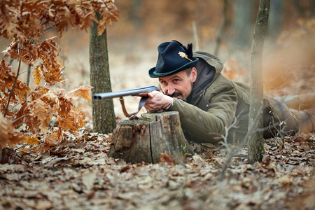Hunter with double barrel gun in the forest looking for game