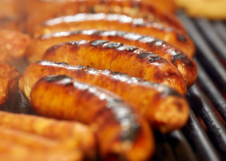 Smoking sausages on the grill in closeup shotの写真素材