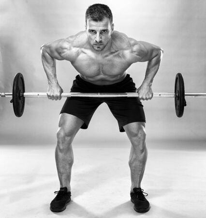 Man doing back workout, barbell row in studio over gray backgroundの写真素材