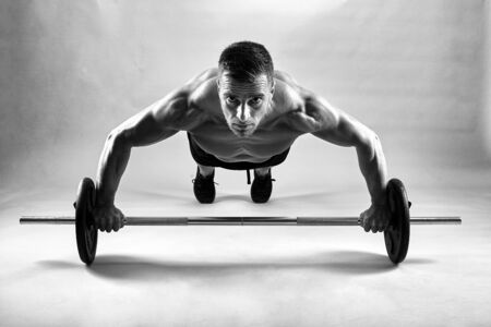 Fitness model doing pushups on gray background in studio