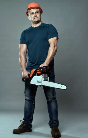 Worker in hardhat holding a chainsaw medium sizeの写真素材
