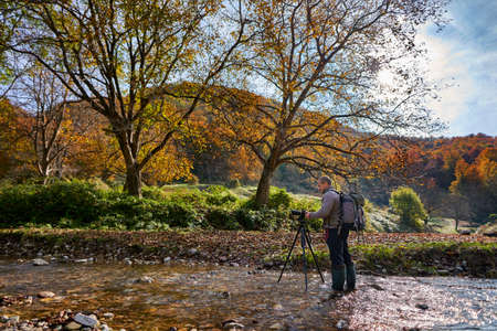 Professional nature photographe with large backpack, camera and tripodの写真素材