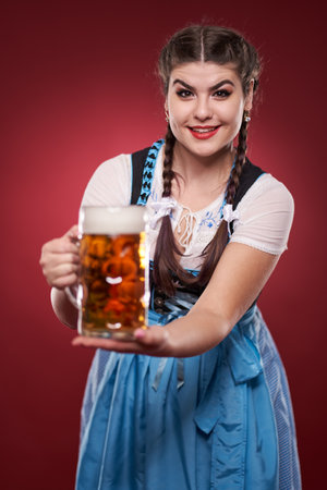 Young woman in traditional German costume holding a pint of pale lagerの写真素材
