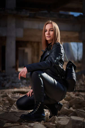 Post apocalyptic portrait of a beautiful young woman in black leather at a ruined industrial facilityの写真素材