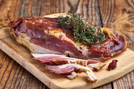 Smoked pork leg on a wooden board in closeupの写真素材