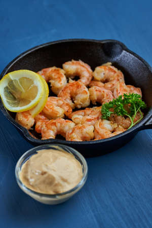 Delicious red king prawns prepared at wok on blue background in a cast iron skilletの写真素材