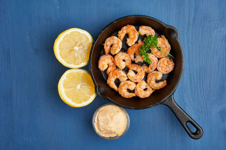 Delicious red king prawns prepared at wok on blue background in a cast iron skilletの写真素材